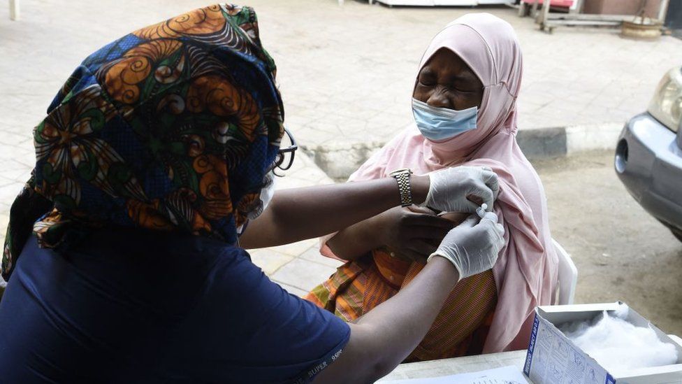 A woman is jabbed by a health worker
