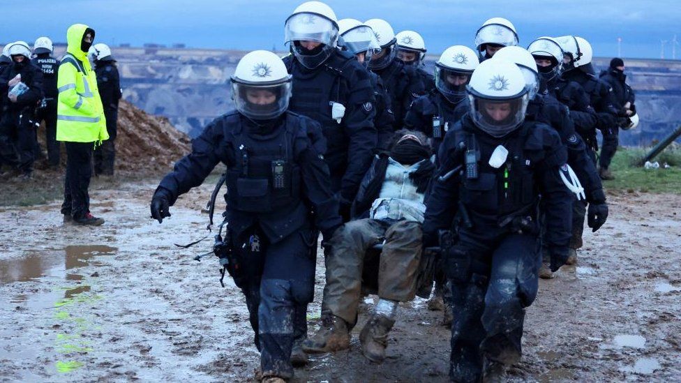 Полицейские несут демонстранта во время климатической акции протеста в Люцерате