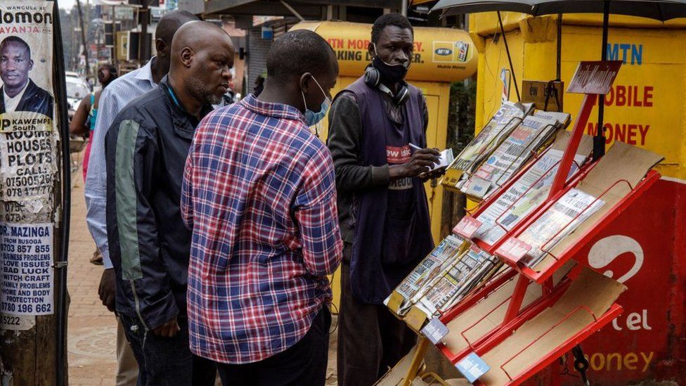 People look at newspapers in Kampala