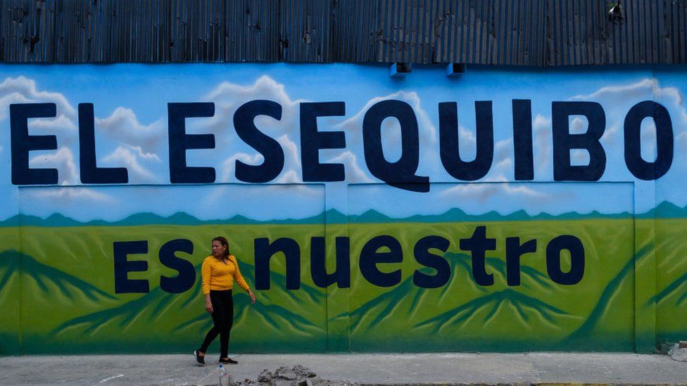 A pedestrian walks past a mural that reads "The Essequibo Is Ours," during a referendum vote in Caracas, Venezuela, on Sunday, Dec. 3, 2023.