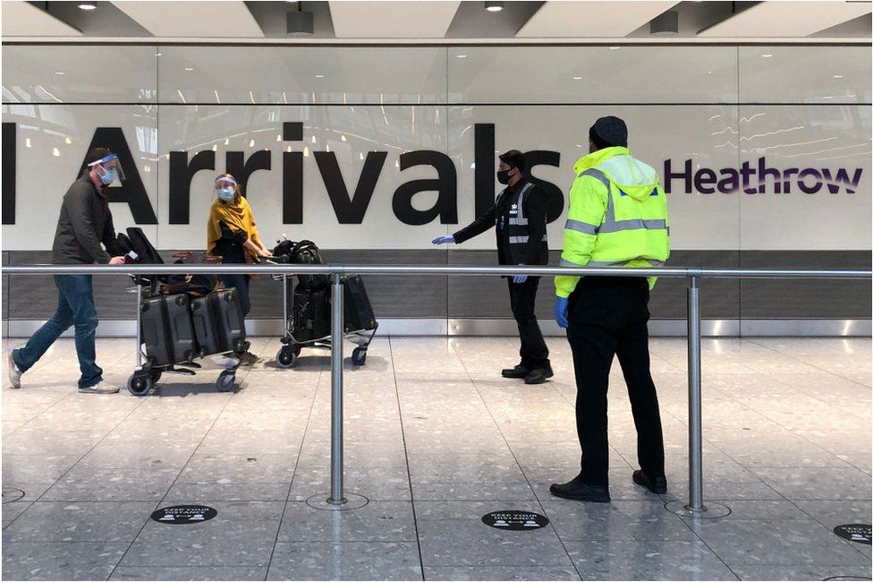 Passengers at Heathrow are guarded as they walk towards a hotel quarantine bus