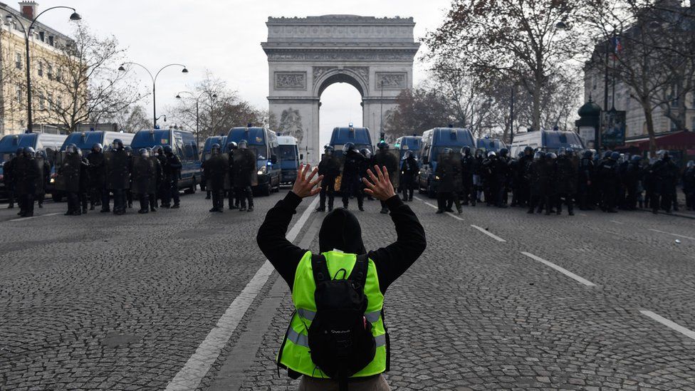 A protester kneels in front of police officers in Paris