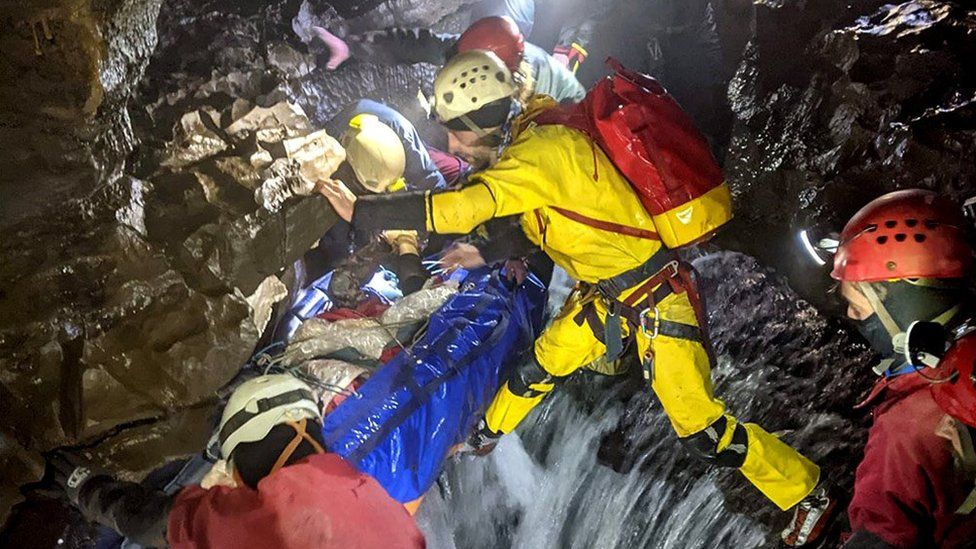 Rescue team carrying injured caver on a stretcher through a cave, 8 November 2021