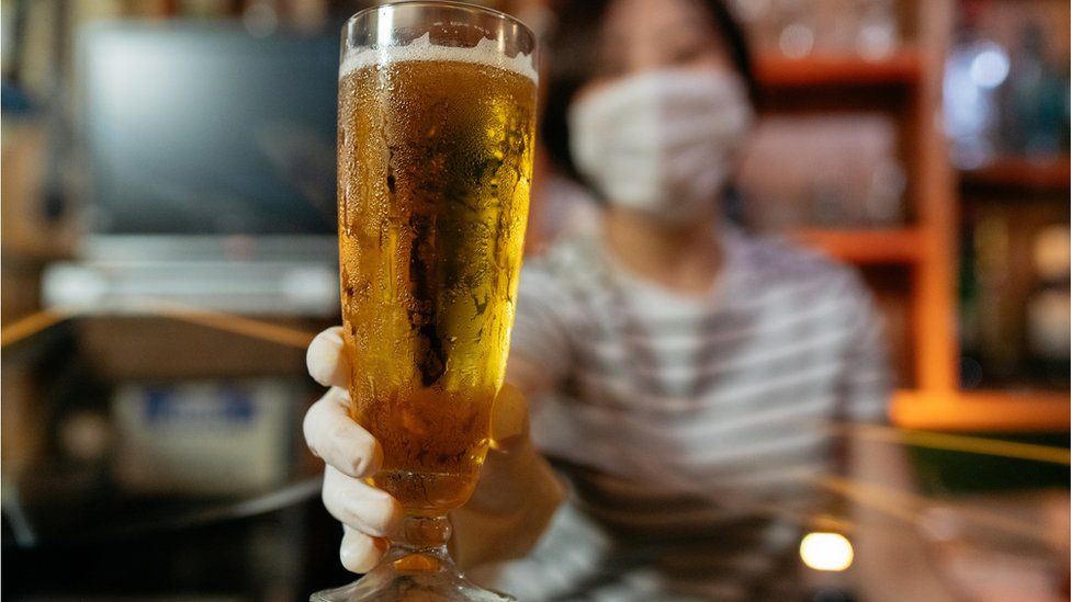 A woman in a mask with a glass of beer