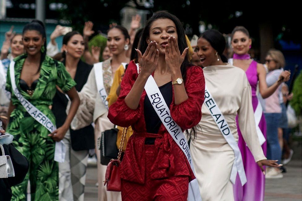 Diana-Lita Hinestrosa Eraul, Miss Universe Equatorial Guinea, blows kisses to the camera as she walks down the street with other contestants.