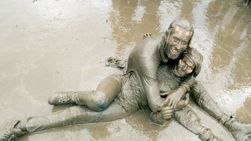 Mud covered couple engaging in a passionate clench at Glastonbury Festival UK 1998