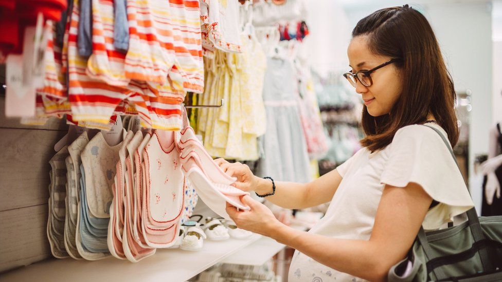 Женщина просматривает детскую одежду в магазине.