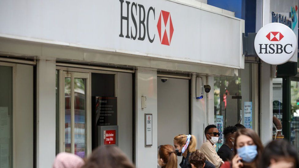Люди, носящие маски в качестве меры предосторожности против распространения covid-19, замечены проходящими мимо Гонконга и Шанхайской банковской корпорации (HSBC) в Анкаре.