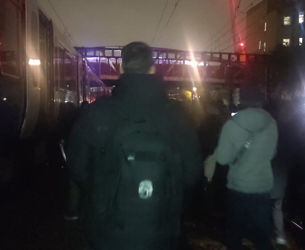 Passengers evacuate from a stranded train in the darkness