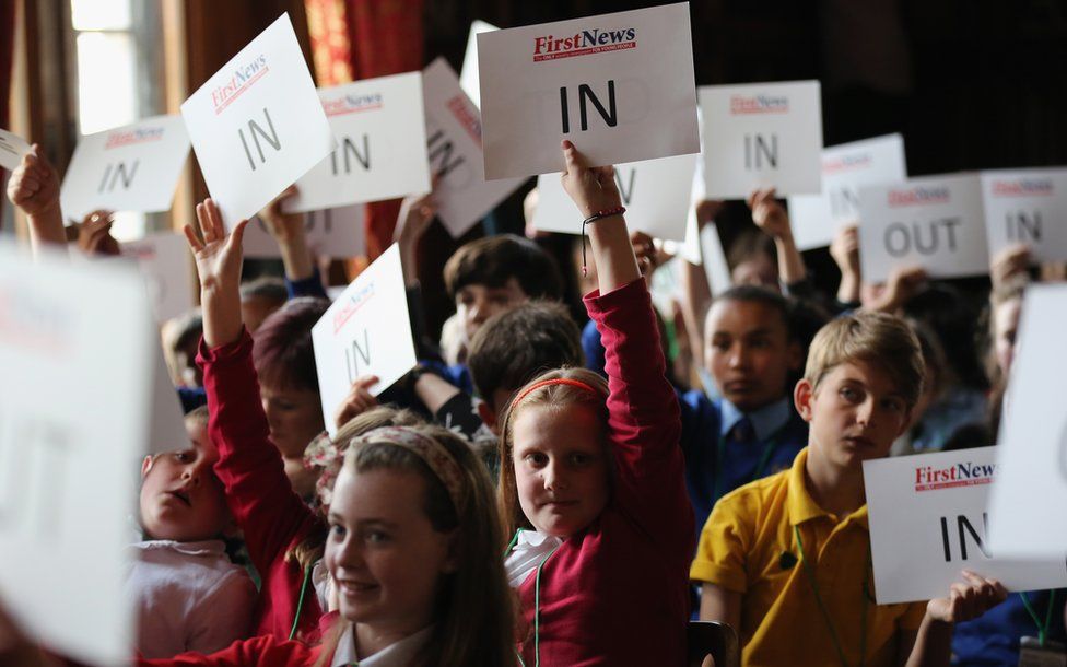 Children of school age holding up "in" and the occasional "out" signs