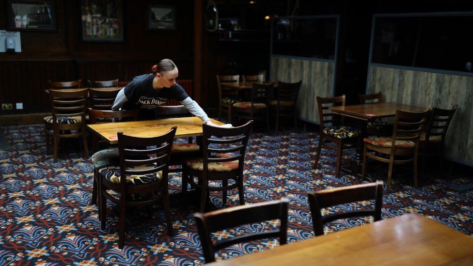 A worker cleans a table in a pub