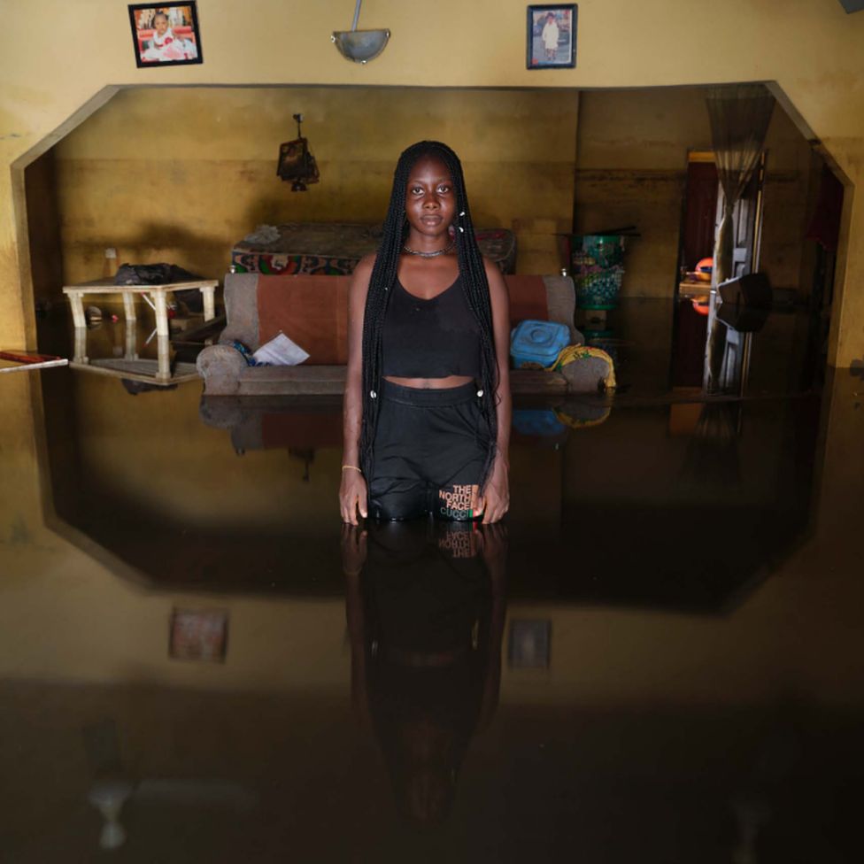 Подарок Икуру стоит в паводковой воде в своем доме в муниципалитете Огбия, штат Байелса, Нигерия, ноябрь 2022 г.
