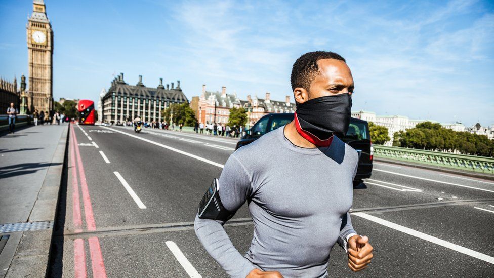 Man jogging by Houses of Parliament with protective mask on