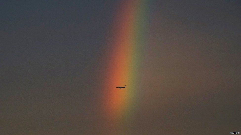 An airplane flies past a rainbow at dusk in Beijing, China on 3 August, 2015