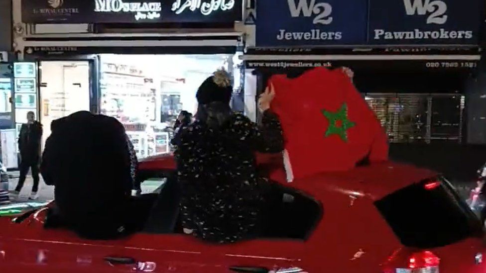 Man waves Moroccan flag out of a car window while it drives down Edgware Road