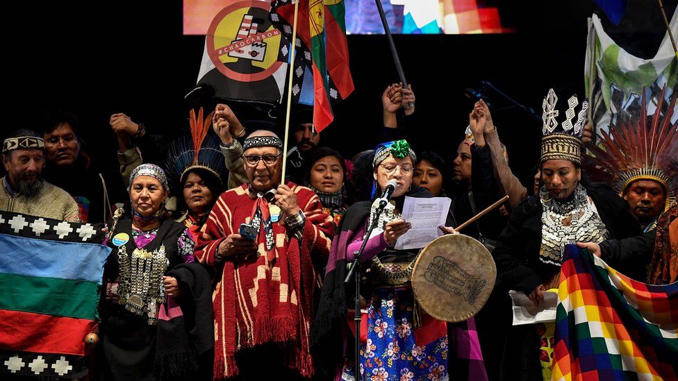 Members of indigenous communities speak onstage after a mass climate march