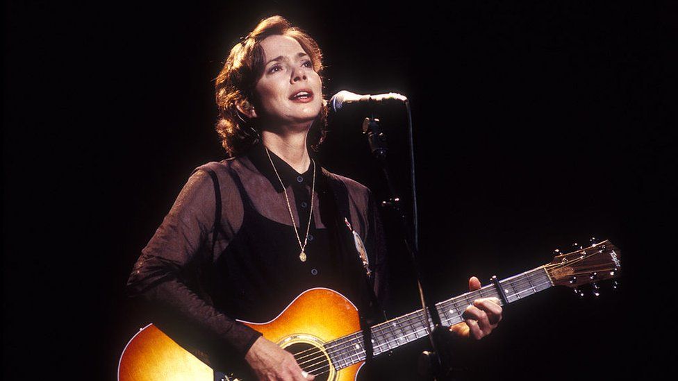1997 image of Nanci Griffith holding a guitar on stage