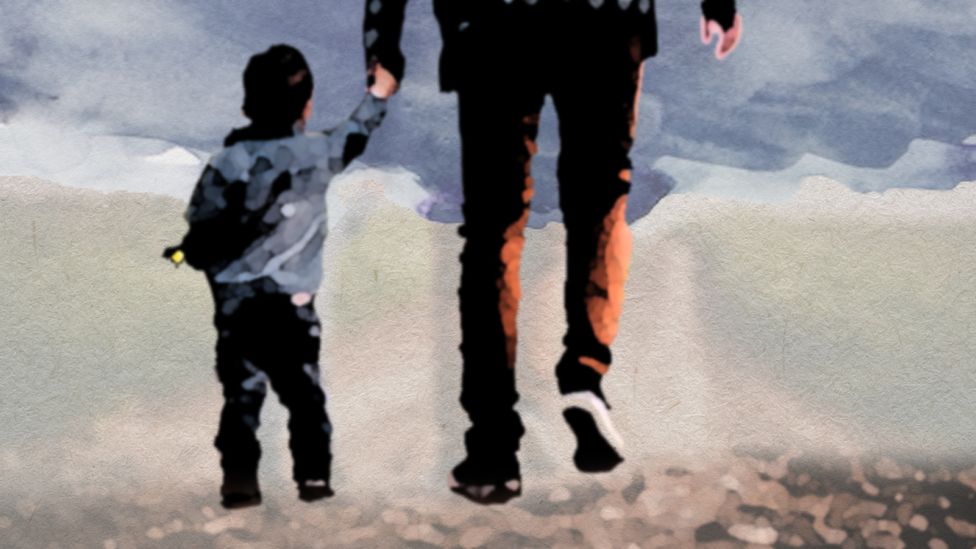 An adult holding a small child's hand and walking away