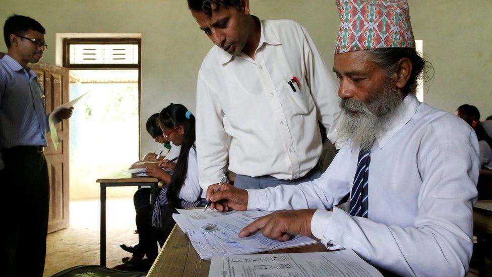 A teacher helps Durga Kami to fill an examination registration form