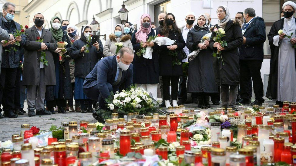Ümit Vural (C), president of the IGGÖ Islamic religious community of Austria, lays down flowers for the victims at a makeshift memorial of candles and flowers at the scene of a terror attack in Vienna,
