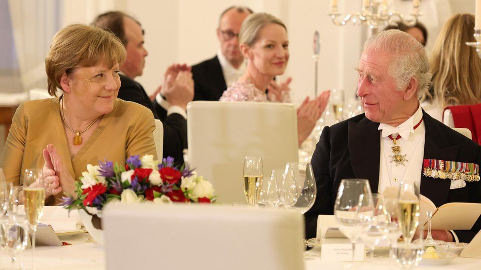 Angela Merkel and King Charles look at each other whilst sat at their table for the state banquet