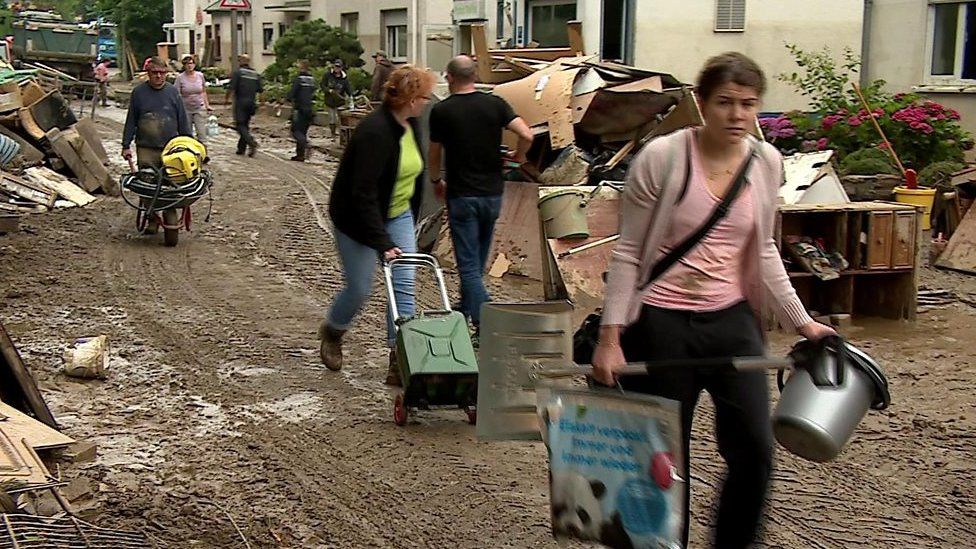 People with belongings walking on muddy road