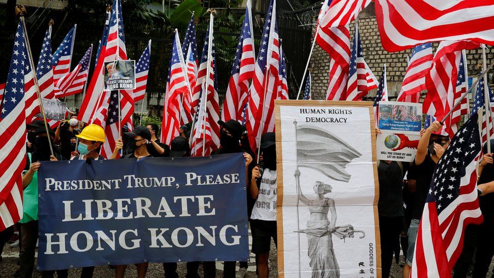 Us flags abound in this photo of protesters standing by a sign which reads "President Trump, Please liberate Hong Kong!"