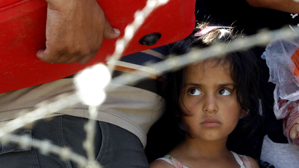A girl looks on from behind barbed wire while waiting with her family to enter into Macedonia from Greece, on the border line between the two countries, near southern Macedonia"s town of Gevgelija, on Wednesday, Aug. 26, 2015.