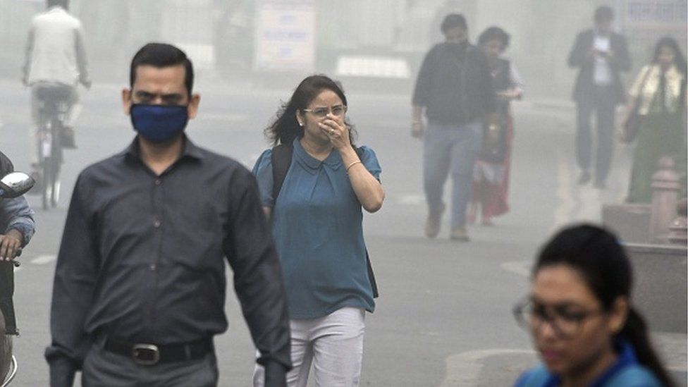 Indian people walk on a street as heavy smogs covers New Delhi on November 8, 2017