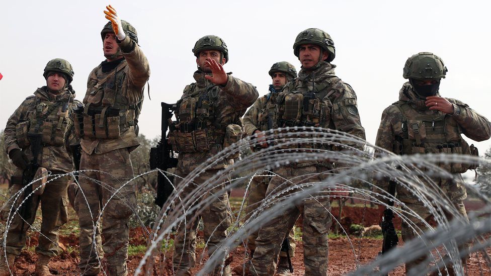 Turkish soldiers stand behind barbed wire at an observation post in Binnish, Idlib province, Syria (14 February 2020)