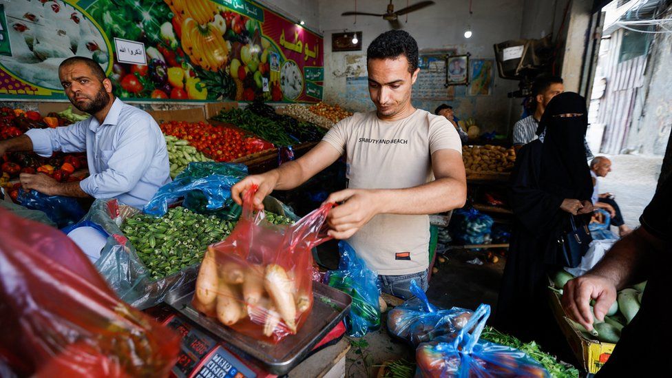 Палестинец взвешивает овощи в магазине, пока соблюдается режим прекращения огня, в Рафахе на юге сектора Газа 8 августа 2022 года.