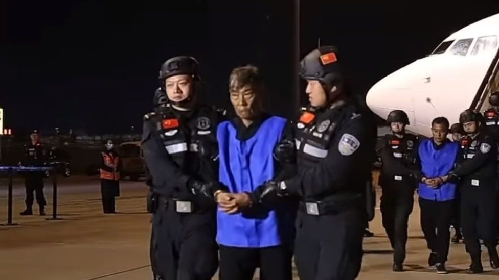 Screenshot of Bai Suocheng being escorted down the plane