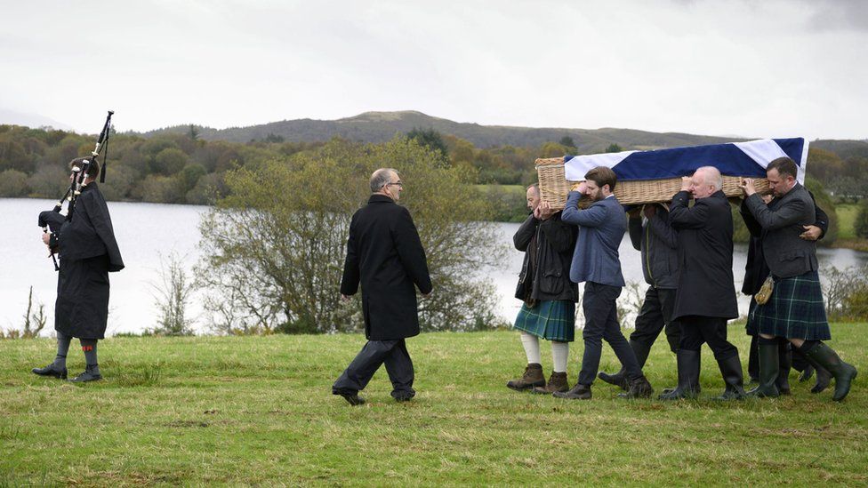 Mourners carrying the coffin of Ian Hamilton KC to his burial in a plot