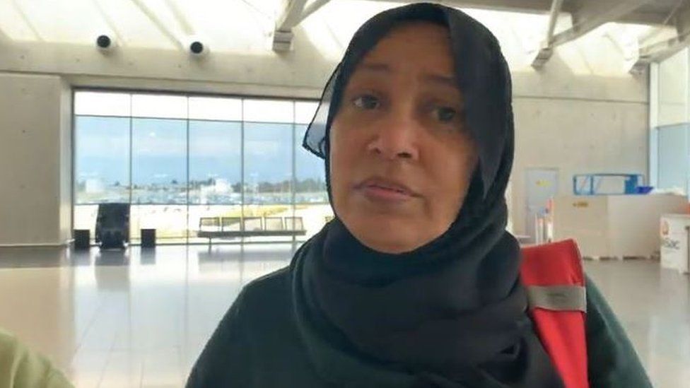 Wafaa Salim pictured at Larnaca Airport in Cyprus. She has a head covering and is wearing a high visibility jacket.