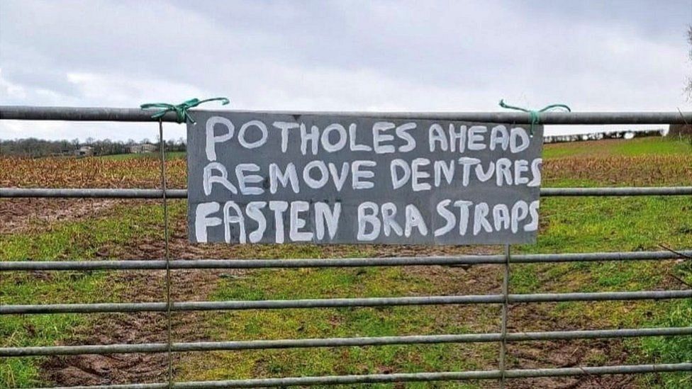 Potholes informing  motion   saying 'potholes ahead, region   dentures, fasten bra straps'