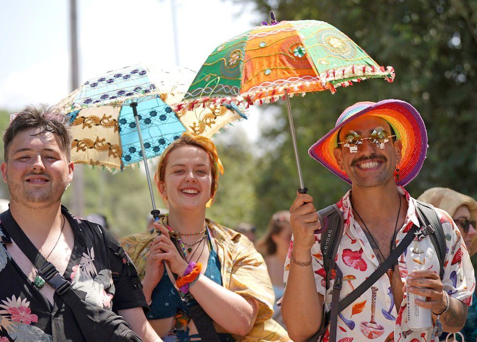 Посетители фестиваля используют зонтики, чтобы защитить себя от солнца в Гластонбери