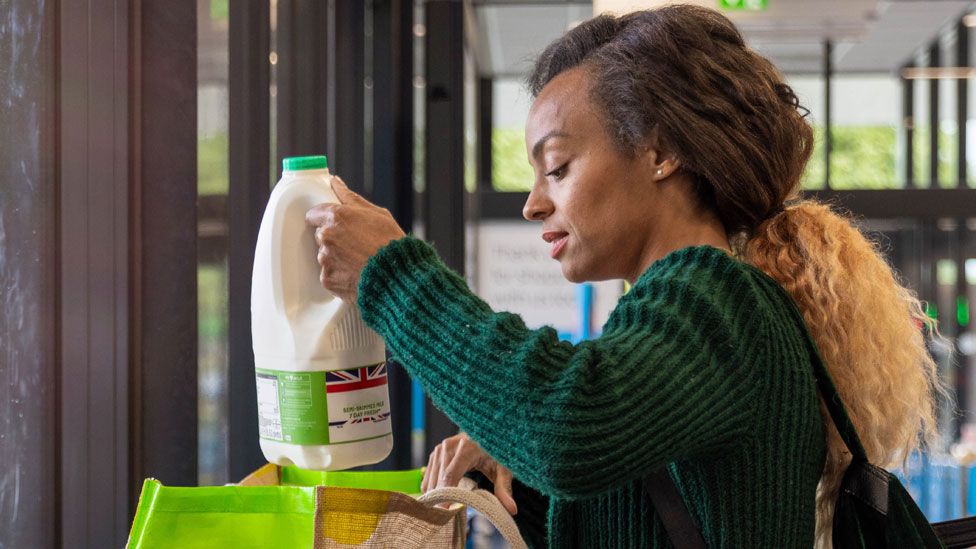 A woman holds a carton of milk in a supermarket