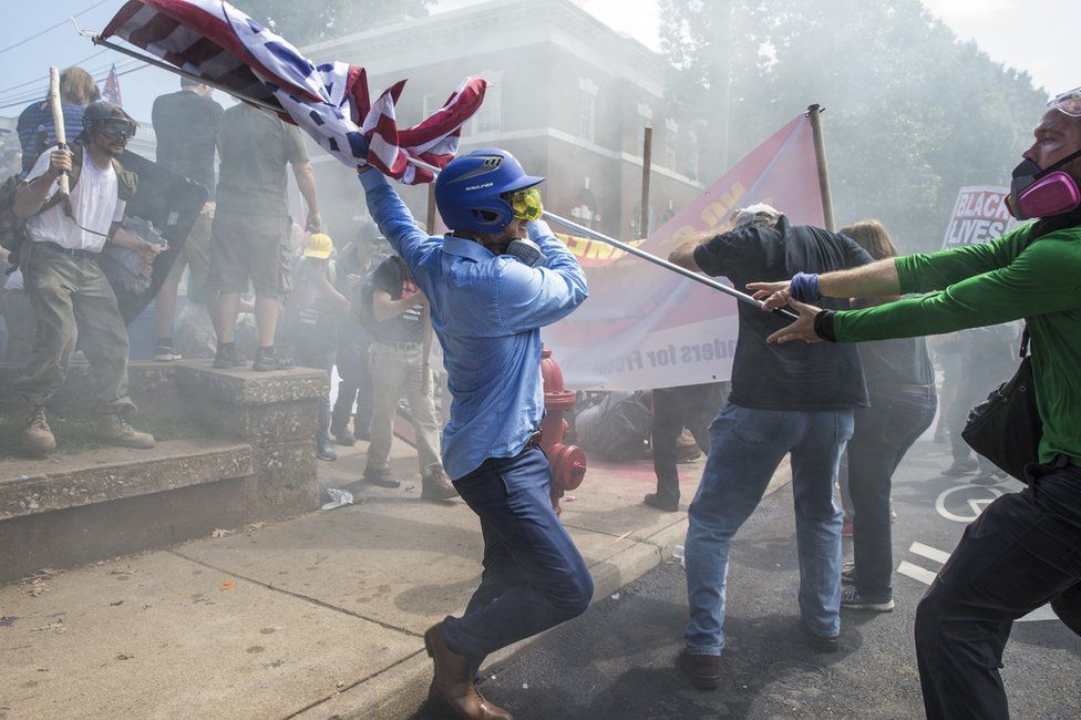 A White Supremacist tries to strike a counter protestor with a White Nationalist flag during clashes at Emancipation Park where the White Nationalists are protesting the removal of the Robert E. Lee monument in Charlottesville, Va., USA on August 12, 2017.