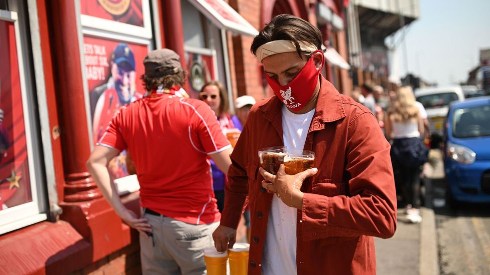 Fan carries beers outside Anfield pub
