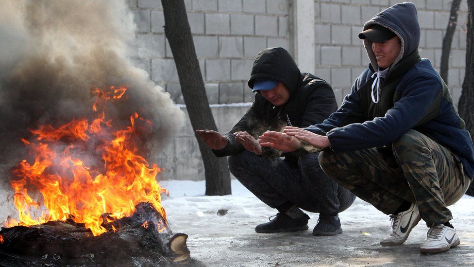 Kyrgyz people warming themselves round a fire in Bishkek, Kyrgyzstan