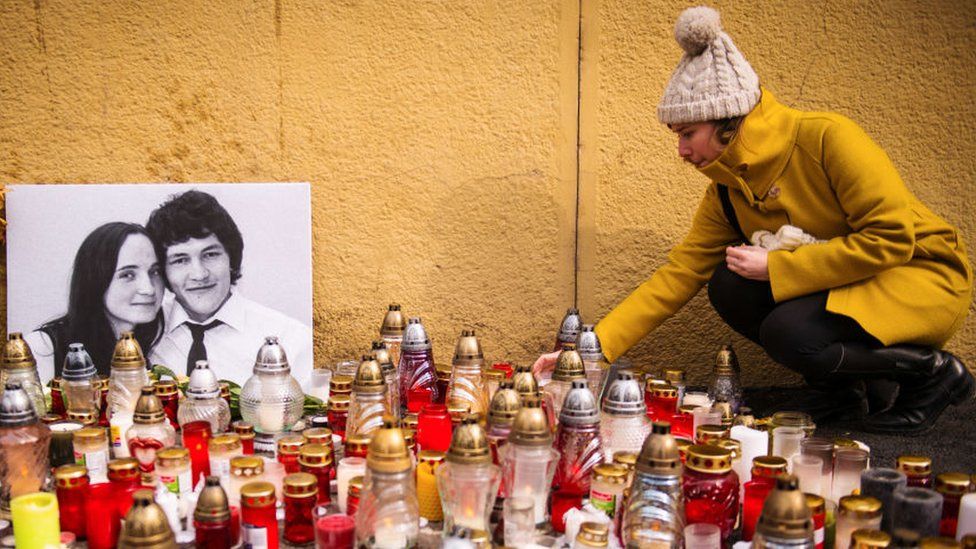 woman places a candle in front of a portrait of Slovak investigative journalist Jan Kuciak and his girlfriend Martina Kusnirova in the centre of Bratislava on February 27, 2018.
