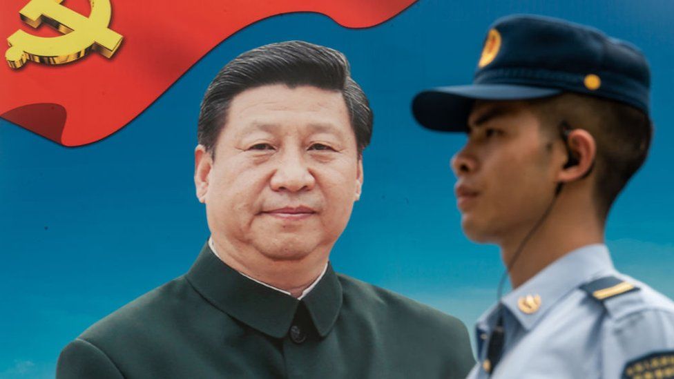 A member of the PLA stands guard in front of a billboard of Xi Jinping