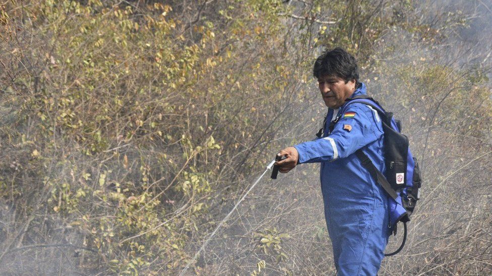 Bolivian President Evo Morales spraying water at a fire in the community of Santa Rosa, near Robore in eastern Bolivia, on August 28, 2019