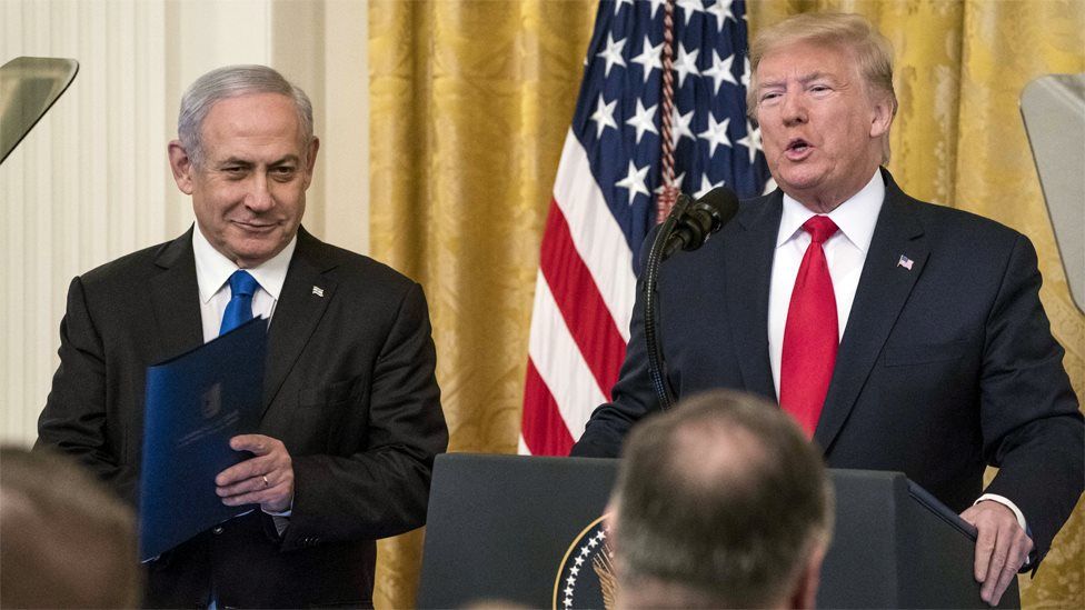 Israeli Prime Minister Benjamin Netanyahu smiles as US President Donald Trump unveils his Middle East peace plan at the White House (28 January 2020)