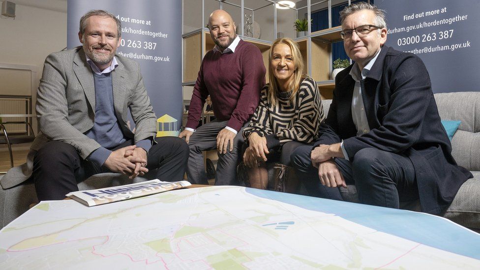 Three men and a woman sit by a map of Horden