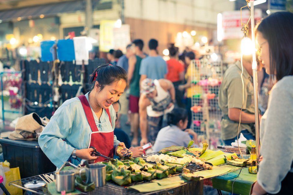 A woman prepares food in a street market