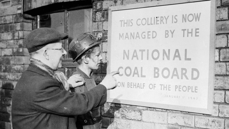 Two miners reading a sign at a colliery informing them of nationalisation