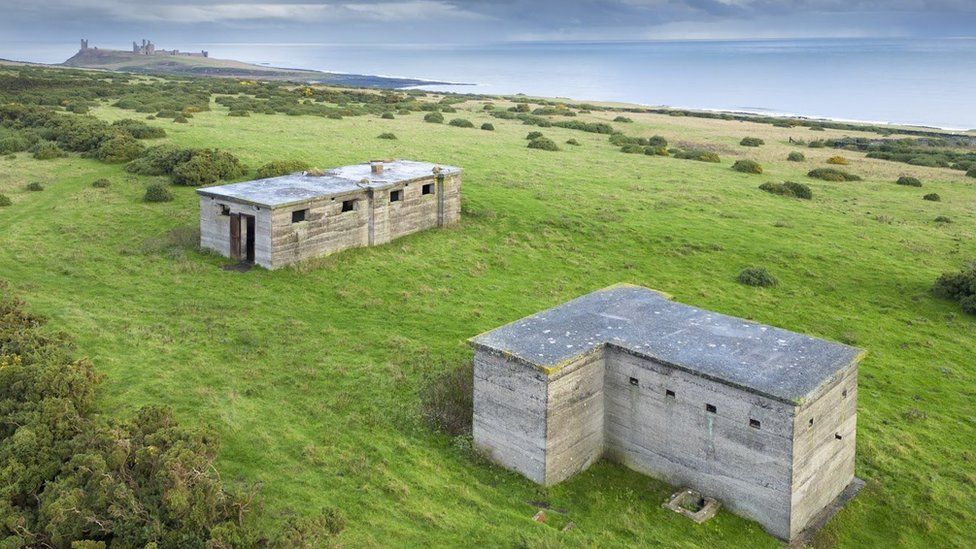 Two concrete bunkers in a field overlooking the sea