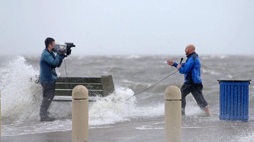 A news crew films as the storm surge pushes water from Lake Pontchartrain