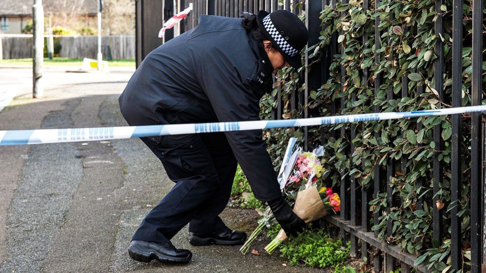 Police officer places flowers at scene of fatal stabbing in London